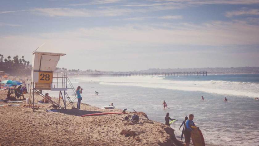 A picturesque view of Pacific Beach, a lifeguard station, surfers and beach enthusiasts enjoying the scenery.