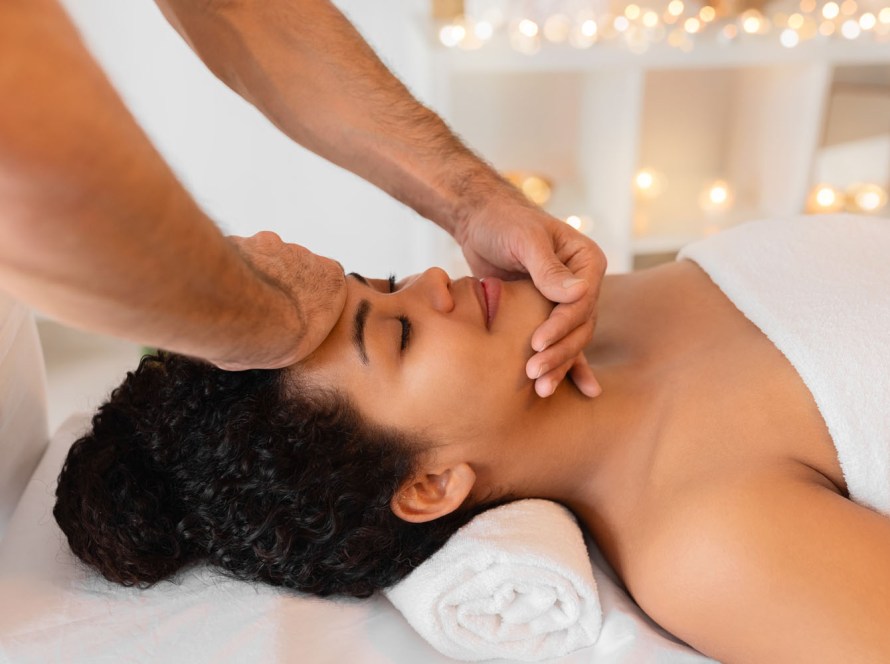 Client enjoying the Beach Bliss spa package in Pacific Beach, featuring a hot stone massage, aromatherapy, facial, ozone steam therapy, full body red light therapy session, and a signature beach tote bag