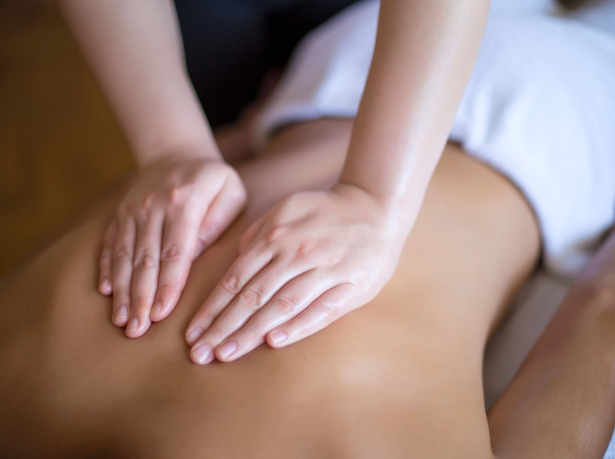 Massage therapists oily hands rubbing an athletic back to soothe & work out tension.